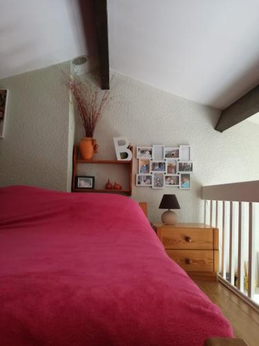 - une chambre avec un lit rouge et une commode en bois dans l'établissement Les Capellans, port d'attache, à Saint Cyprien Plage