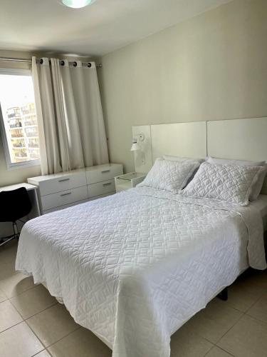 a bedroom with a white bed and a window at Barra Family Resort com piscina e spa, 2 quartos in Rio de Janeiro
