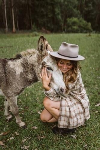 a woman in a hat is hugging a donkey at Banksia at barranca KV - Luxury Villa in Kangaroo Valley