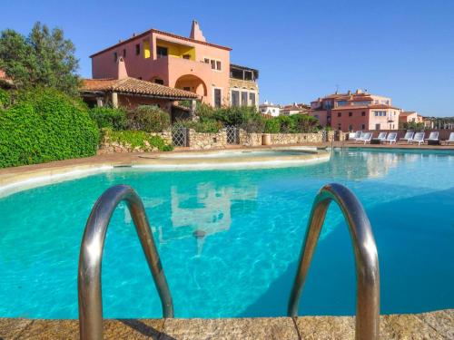 a swimming pool with blue water in front of a house at Apartment La Capitaneria in Porto Cervo