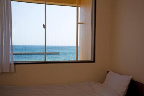 a bedroom with a window with a view of the ocean at Harbor Hotel Kaigetsu in Sumoto