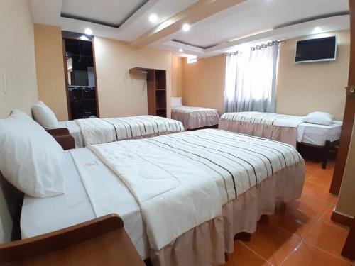 ein Krankenzimmer mit drei Betten und einem Fernseher in der Unterkunft Hotel El Gran Patriarca in Cajamarca