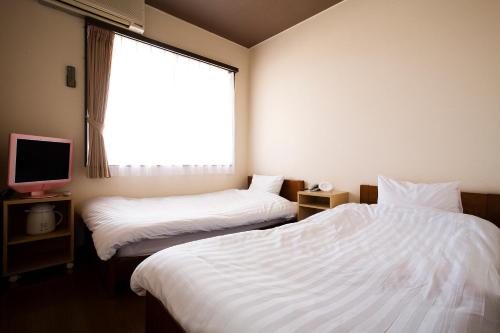 um quarto de hotel com duas camas e uma janela em Harbor Hotel Kaigetsu em Sumoto