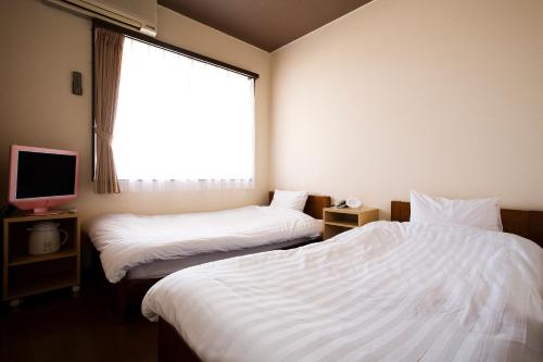 洲本市にあるハーバーホテル海月のベッド2台と窓が備わるホテルルームです。