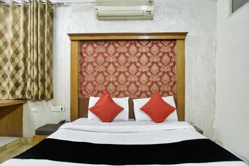 Un dormitorio con una cama con dos almohadas rojas. en Collection O Udit Plaza, en Bhopal