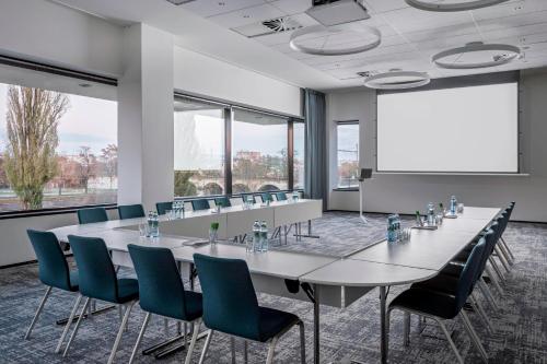 a conference room with a long table and chairs and a white screen at Courtyard by Marriott Brno in Brno