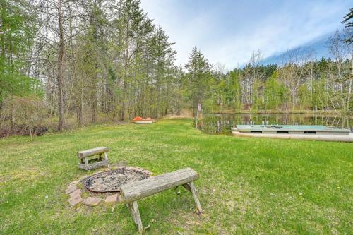 a park bench sitting in the grass next to a lake at Spacious Sterling Cabin Game Room, Private Pond! in Sterling