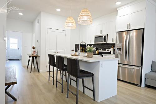 a kitchen with white cabinets and a kitchen island with bar chairs at Chic Modern Home,King Bed,Fireplace,Disney in Edmonton