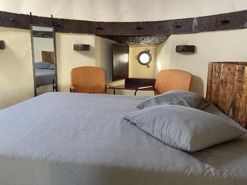 a bedroom with a bed with two chairs and a table at Moinho da Boavista in Serra do Bouro