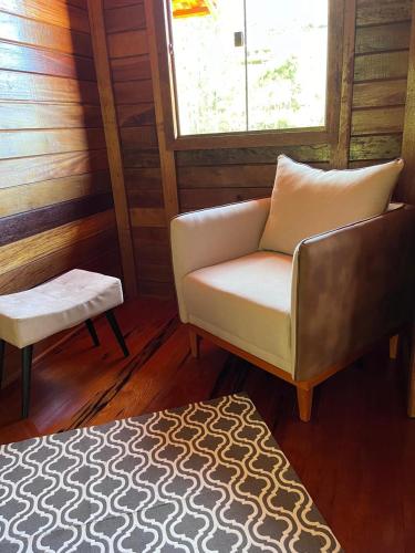 a living room with a chair and a stool at Hospedagem Recanto Pedra Azul in Domingos Martins