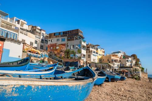 a group of boats sitting on a beach with buildings at Appartement Taghazout in Taghazout