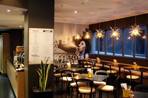 a restaurant with tables and chairs and a painting on the wall at Mantra on Little Bourke Melbourne in Melbourne