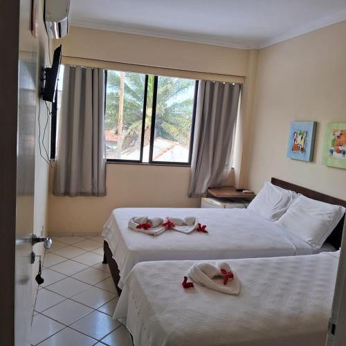 a hotel room with two beds with red roses on them at Pousada Village in Barreirinhas