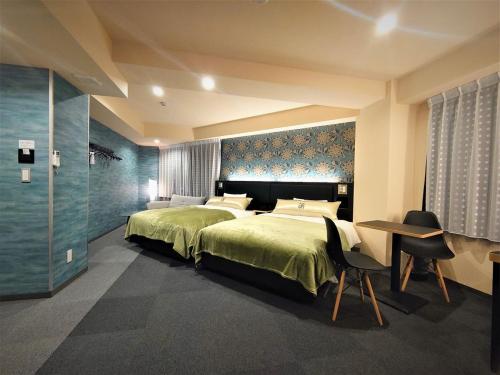 a bedroom with a green bed and a table and chairs at Green Rich Hotel Kyoto Station South (Artificial hot spring Futamata Yunohana) in Kyoto
