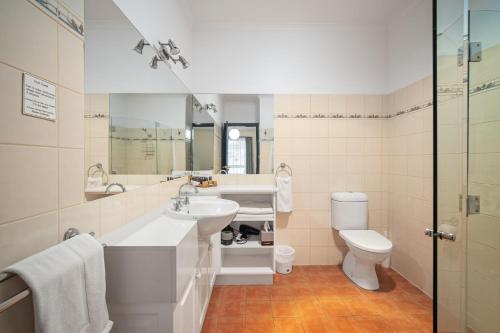 a bathroom with a sink and a toilet and a mirror at The Lawson Riverside Suites in Wagga Wagga