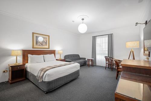 a hotel room with a bed and a desk at The Lawson Riverside Suites in Wagga Wagga