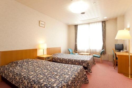 a hotel room with two beds and a desk at Sunrise Awaji in Minamiawaji