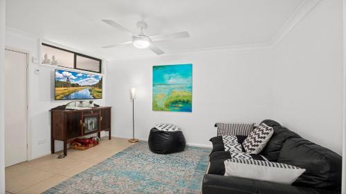 a living room with a black couch and a table at Town Terrace 8 in Sawtell