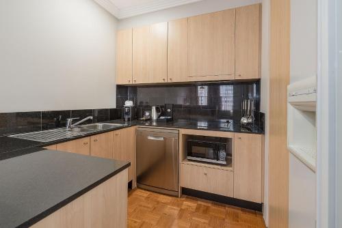 a kitchen with wooden cabinets and a sink and a dishwasher at Mantra on Little Bourke Melbourne in Melbourne
