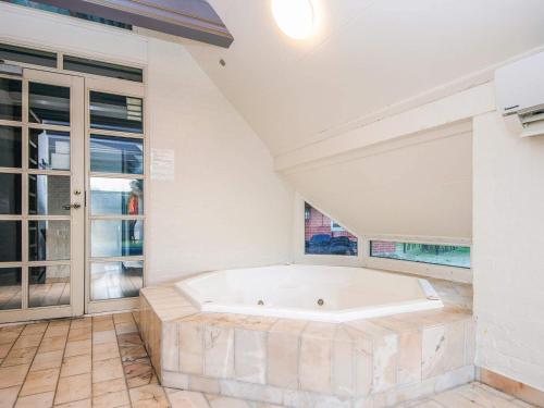 eine große weiße Badewanne in einem Raum mit Fenstern in der Unterkunft 4 star holiday home in Blåvand in Blåvand