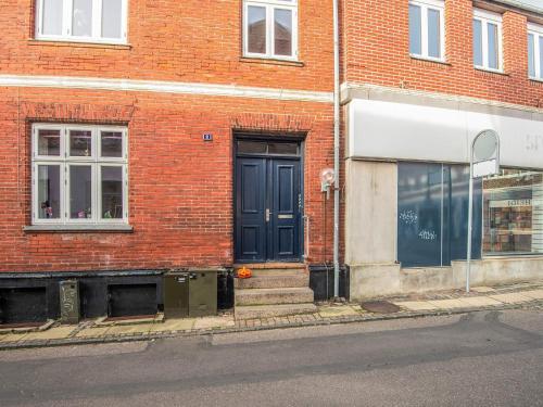 a brick building with a black door on a street at 6 person holiday home in Ringkøbing in Ringkøbing
