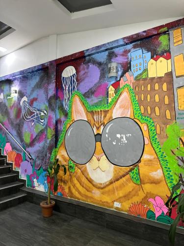 a painting of a cat wearing glasses on a wall at Hotel Bestmark Platino en Chapinero Bogota in Bogotá