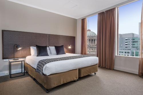 a hotel room with a large bed and a large window at Mantra on Little Bourke Melbourne in Melbourne
