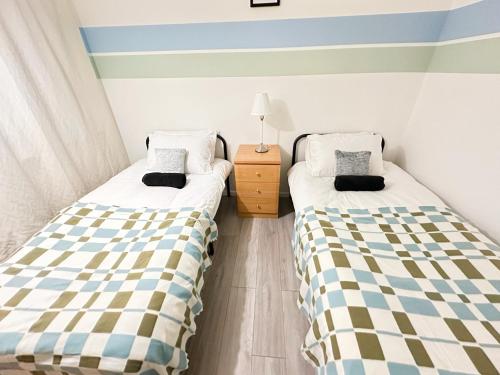 two beds sitting next to each other in a room at Spacious Luton Airport Accommodation - Perfect for Contractors, Families, Tourists & Long Stays in Luton