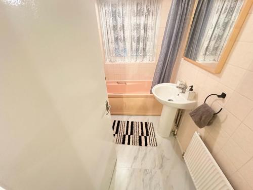 a bathroom with a sink and a toilet and a window at Spacious Luton Airport Accommodation - Perfect for Contractors, Families, Tourists & Long Stays in Luton