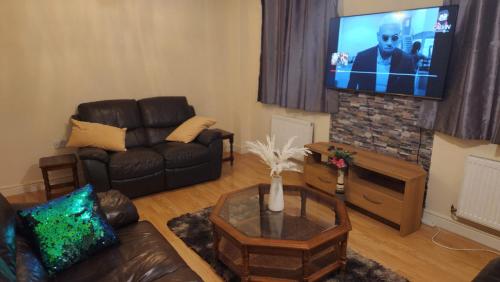 a living room with a couch and a flat screen tv at Mekees Luxury Apartment in Tipton