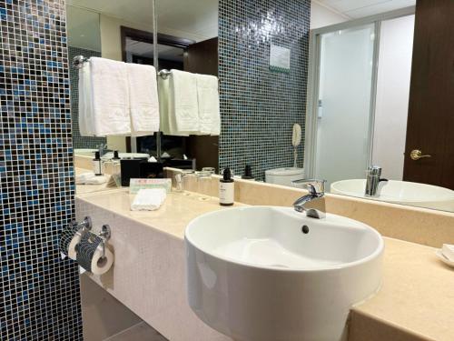 un bagno con un lavandino bianco e uno specchio di Metropark Hotel Kowloon a Hong Kong