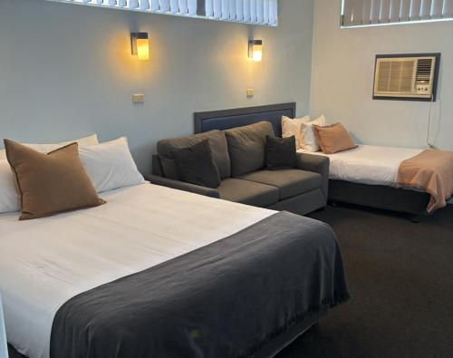 a hotel room with two beds and a couch at Tall Timbers Motel in Dungog