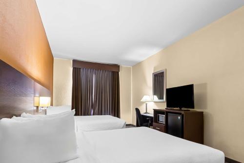 a hotel room with two beds and a flat screen tv at Best Western St. Louis Airport North Hotel & Suites in Hazelwood
