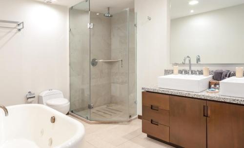 a bathroom with a shower and two sinks and a toilet at Condo de lujo en Mazatlan Peninsula in Mazatlán