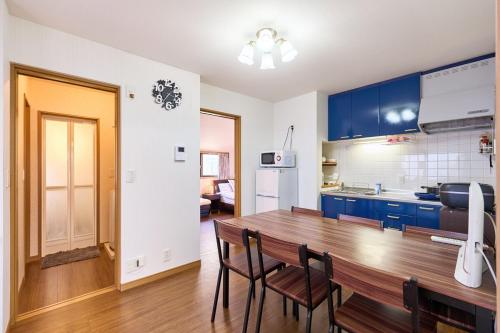 a kitchen with blue cabinets and a wooden table and chairs at 2LDK Quiet area Free parking space 6min from station in Tokyo