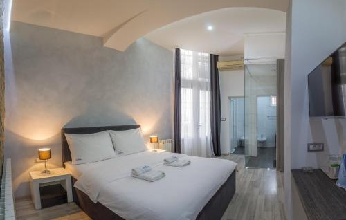 a bedroom with a large white bed and a bathroom at Central Park Residence in Belgrade