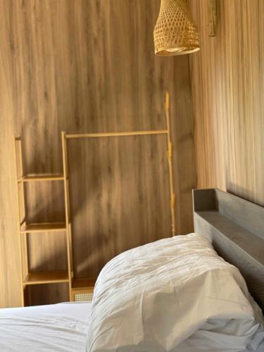 a bedroom with a bed and a wooden wall at Giăng's House Farmstay & Glamping in Bao Loc