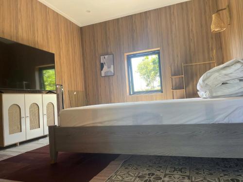 a bedroom with a large bed and a television at Giăng's House Farmstay & Glamping in Bao Loc