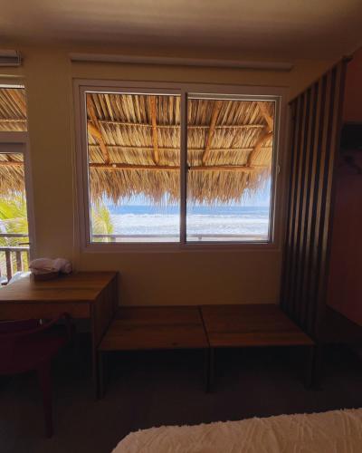 a room with a window with a bench and a table at BungaLoose Casa Waimea Oceanfront in Sipacate