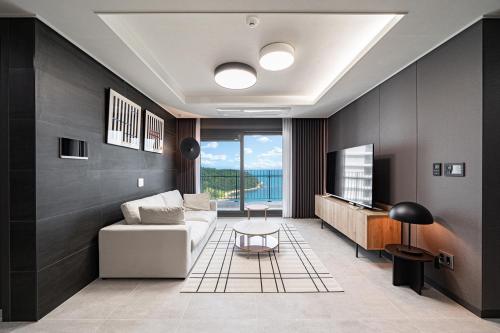 a living room with a couch and a tv at Le Collective Busan Gijang in Busan