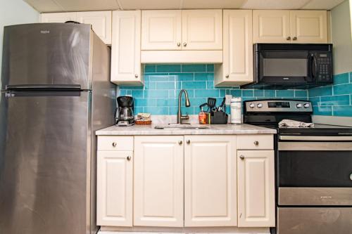 a kitchen with white cabinets and a stainless steel refrigerator at Pet Friendly Modern Oceanfront Suite in Myrtle Beach