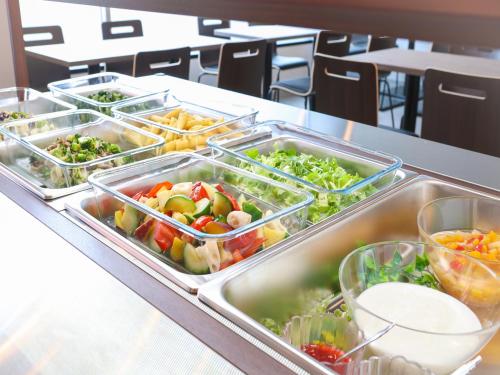 a buffet with several trays of vegetables on a table at APA Hotel Hakodate Ekimae in Hakodate