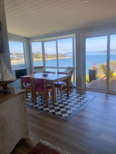 a dining room with a table and a view of the ocean at Beach Buoy Opossum Bay in South Arm