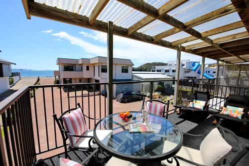 a patio with a glass table and chairs on a balcony at Blue Marlin Apartments in Whitianga
