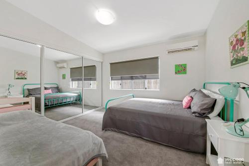 een slaapkamer met twee bedden en een spiegel bij Air-conditioned Cooee Bay Beach House with Wi-Fi in Yeppoon
