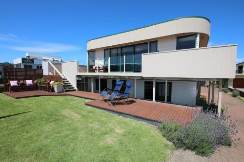 a house with two chairs sitting on a lawn at Blue Marlin Apartments in Whitianga