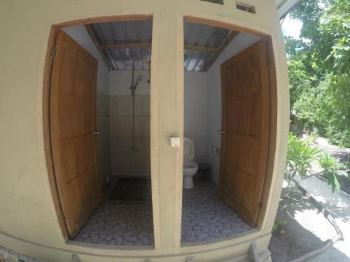 a bathroom with two wooden doors and a toilet at SELAYAR TURTLE BAY in Barangbarang