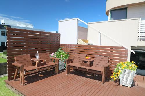 a patio with two benches and flowers on a deck at Blue Marlin Apartments in Whitianga