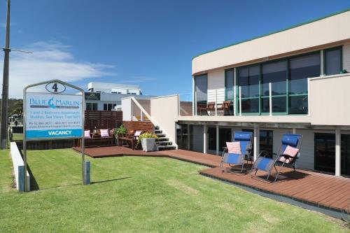 a building with chairs and a sign in front of it at Blue Marlin Apartments in Whitianga