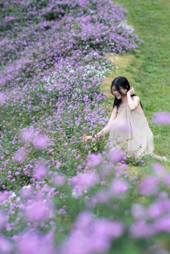 a woman walking through a field of purple flowers at Mây home Trạm Tấu nhà sàn cộng đồng in Trạm Tấu